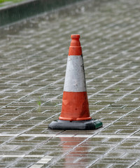 white-orange road cone on a rainy day
