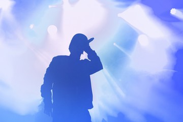 Silhouette of rap singer performing on concert. Rapper singing on stage in night club. Hip hop music poster template. Blue background with cool musician for wallpaper design - obrazy, fototapety, plakaty