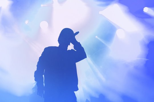 Silhouette of rap singer performing on concert. Rapper singing on stage in night club. Hip hop images for poster design - Powered by Adobe