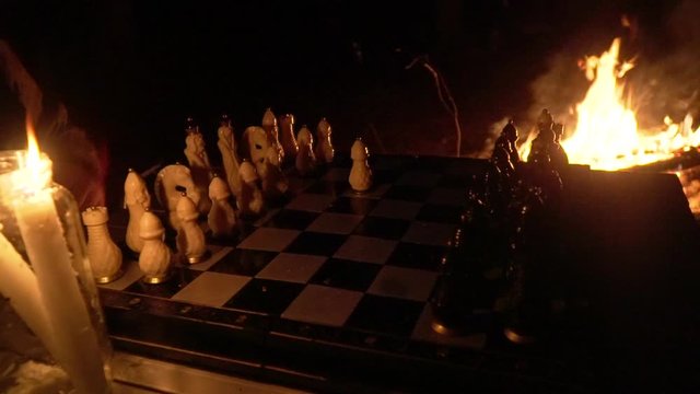 game of chess against the backdrop of the fire, the beginning of the game a pawn move, close up