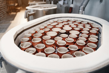 Man taking ceramic cups from the electric oven at the pottery, close-up view
