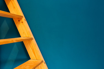 wooden yellow ladder on blue wall background. colorfull interior abstract
