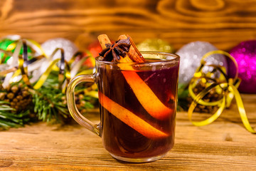 Cup of mulled wine with cinnamon, christmas decorations and fir tree branches on wooden table