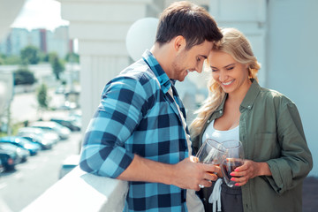 Cheerful couple laughing while drinking coffee on balcony