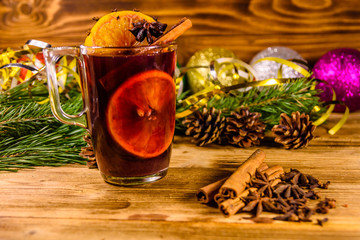 Cup of mulled wine with cinnamon, christmas decorations and fir tree branches on wooden table