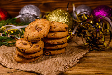 Stack of the chocolate chip cookies on sackcloth in front of christmas decorations