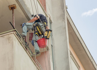 work on building facade from worker suspended with ropes