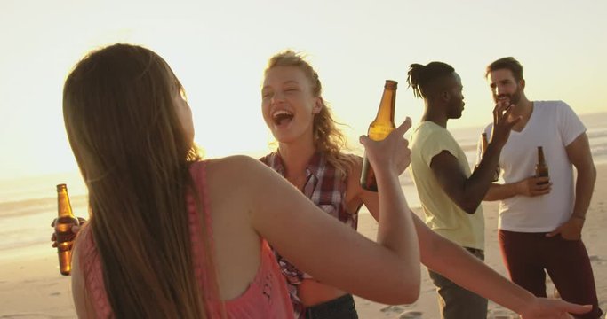 Young adult friends drinking on a beach at sunset 4k