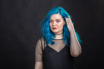 Obraz premium People and fashion concept - Young and attractive woman with black lipstick and blue hair posing over black background