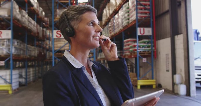 Female warehouse manager talking with headset in loading bay 4k