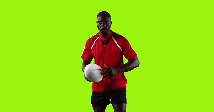 Professional rugby player standing and pointing with a ball on green background 4k