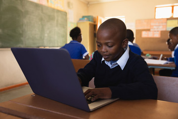 Schoolboy using laptop in a lesson at a township school
