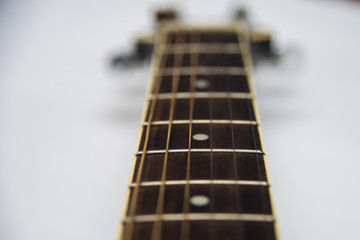 Guitar fretboard close-up top view of the neck of the guitar and strings on white isolated background. Acoustic guitar perspective along fretboard