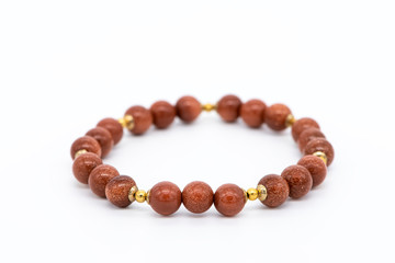 Bracelet made of gold aventurine gemstone on a white background, close-up, selective focus.