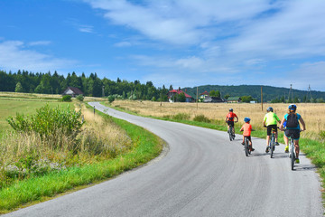 Rear view of a happy family riding bicycles on country road. They get a lot of fun riding together.