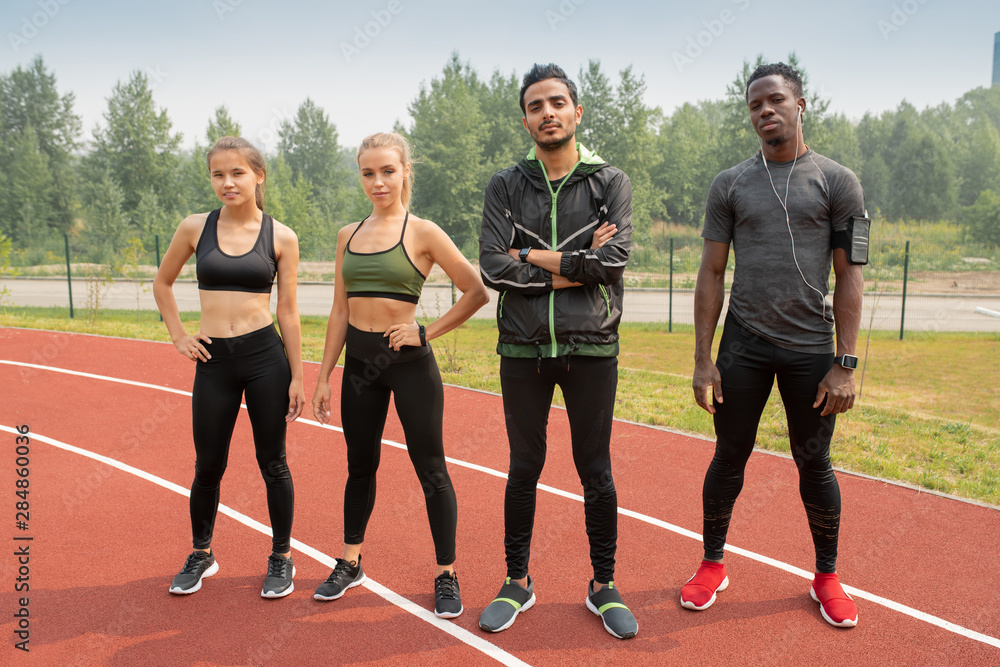 Sticker Row of young intercultural athletes in sportswear standing on racetracks