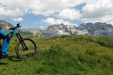 man with electric bike, e-bike, ebike, looking mountains of Brenta Peak, Grostè Pass, meadow, Dolomites, Madonna di Campiglio, summer, sport, adventure, travel, Alps, Trentino Alto Adige, Italy