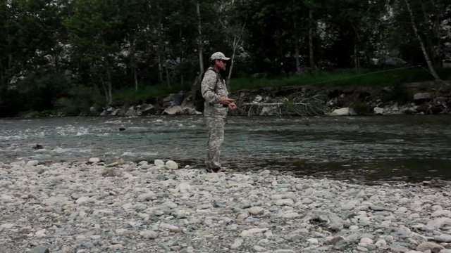 single fisherman on a stormy river is fishing on a sunny summer day