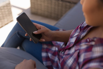 Woman using mobile phone on the terrace at home