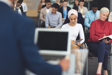 Business people writing notes at a business seminar 