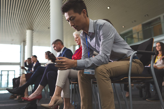 Young businessman using mobile phone during business seminar