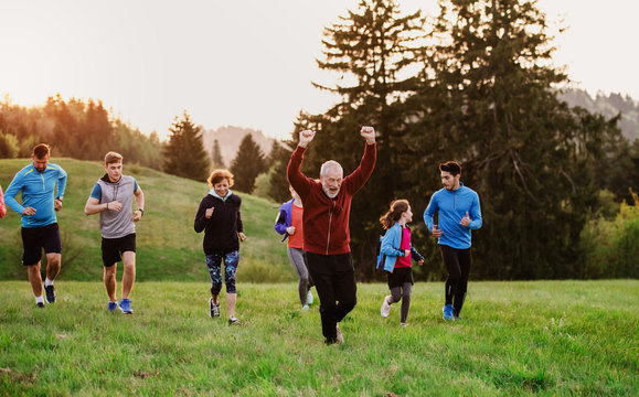 Large group of people cross country running in nature.