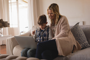 Fototapeta premium Mother with her son using laptop in living room
