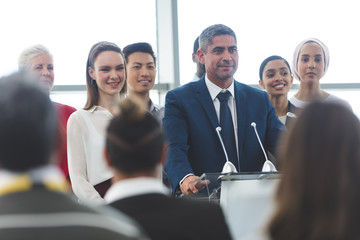 Businessman standing at podium with colleagues and speaks in a business seminar
