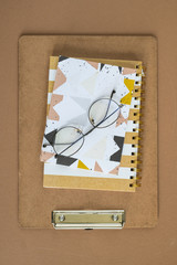 Overview of clipboard, notebook, notepad and eyeglasses on top