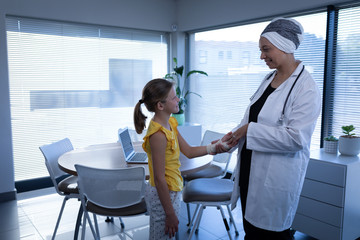 Obraz premium Matured female doctor interacting and examining girl hand in clinic