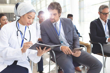 Female doctor discussing with businessman during seminar