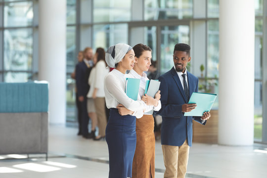 Business executives standing with files in lobby office 