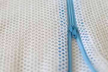 White mesh bag with blue zipper for washing machine.