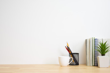 Office desk with supplies, and white wall.