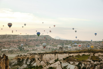 Goreme, Turkey / May, 2019 - Numerous hot air balloons all lift into the air just after dawn