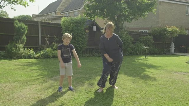 Caucasian boy and his grandmother doing the viral floss dance in their garden themes of childhood family humour dancing