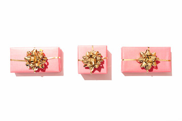 Line of three pink gift boxes on white table