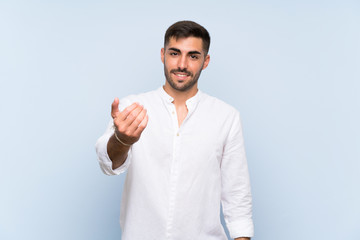 Handsome man with beard over isolated blue background inviting to come with hand. Happy that you came