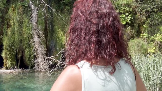 a woman looking at a waterfall in Plitvice, Croatia - travel concept