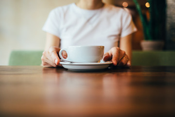 Close-up of female's hands holding saucer