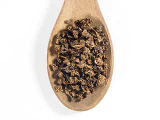 Fermented granular tea from Cherry (Cerasus) leaves in wooden spoon on white background