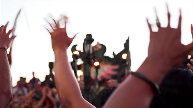 Many hands in the air of indonesian men performing traditional Kecak dance which storyline is taken from Ramayana Hindu epic. Colorful beast on the stage. Uluwatu temple, evening