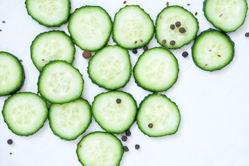 Slices of fresh cucumber and spices. Close-up on a white wooden background.