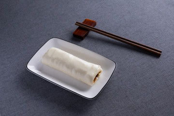 A steamed bun just steamed out of the oven, sandwiched with soybean sauce, was neatly placed in the porcelain plate of the dining table.