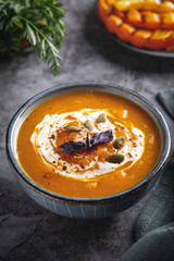Pumpkin cream soup in the bowl, close-up.  Slices of grilled pumpkin. Gray background.