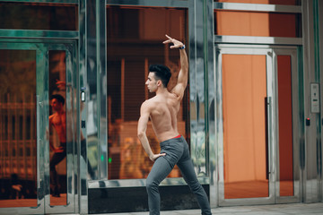 Young male ballet dancer on a building background. Outdoor dance.