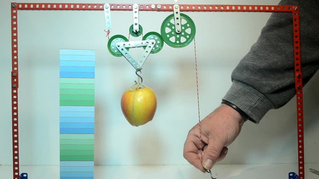 Demonstration of a hoist featuring one method of a double pulley block. The person only has to lift 1/4 of the weight, but must haul a longer distance.