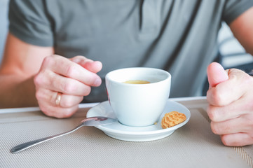 Men's hand with cup of fresh aromatic coffee at table.