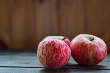 Three red ripe apples on wooden background