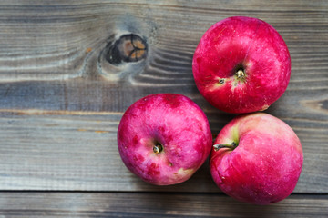 Three red ripe apples on wooden background